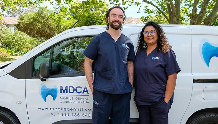 Dentist and Dental assistant standing in front of a van