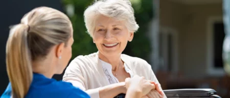 Elderly woman holding a nurse's hand