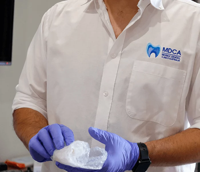 a Dental prosthetist holds a bubble-wrapped new denture