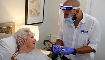 Dental prosthetist showing denture to elderly woman