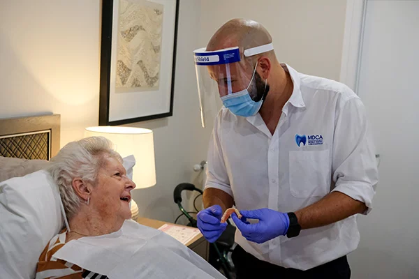 A dental prosthetist holds a newly made denture to be inserted