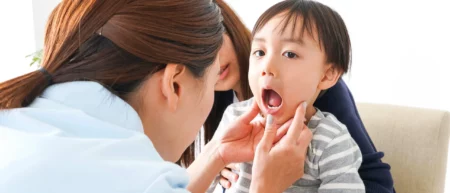 A dentist is checking inside the mouth of a young toddler