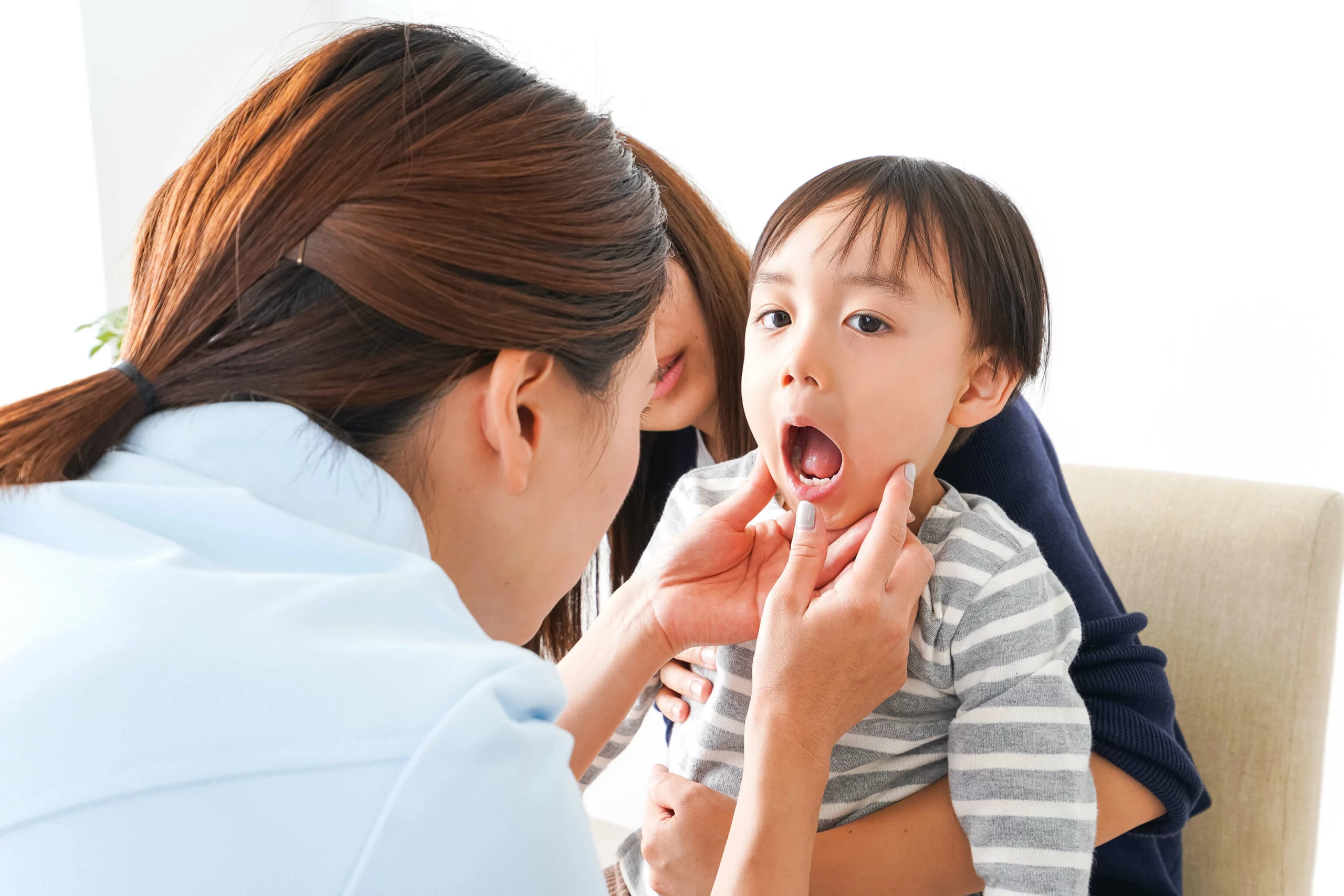 A dentist is checking inside the mouth of a young toddler