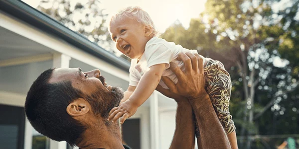 A man holds his smiling toddler up