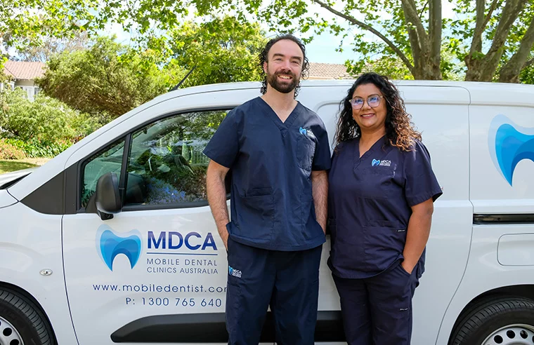 Dentist and Dental assistant standing in front of a van