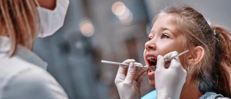 A dentist examines a young girl's teeth