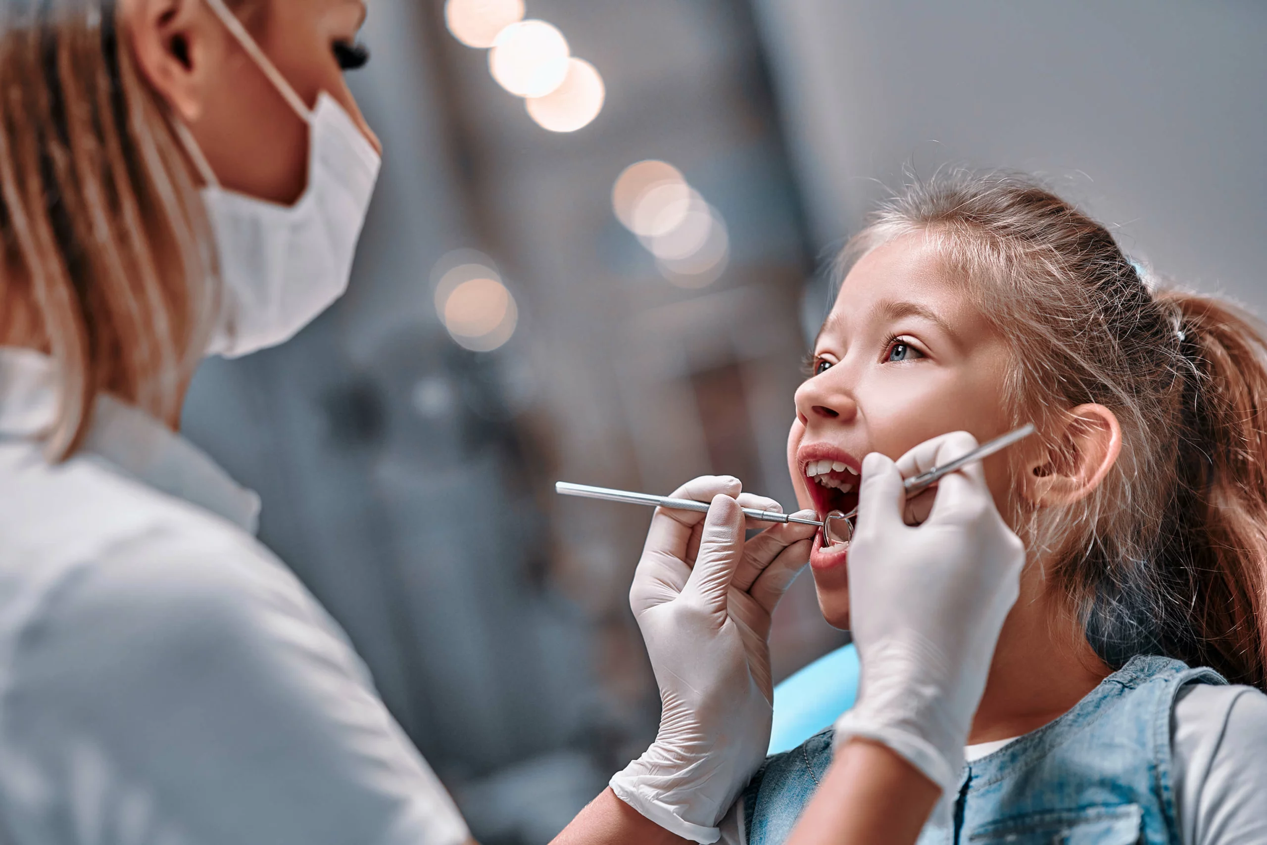 A dentist examines a young girl's teeth