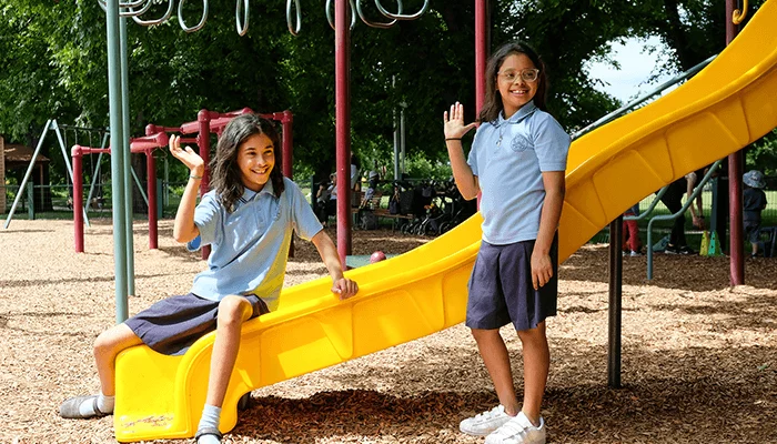 Two school children wave to the dentists in a park