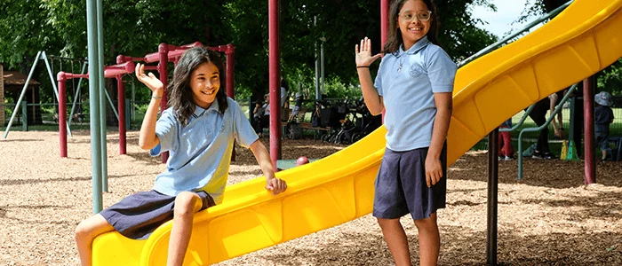 Two school children wave to the dentists in a park